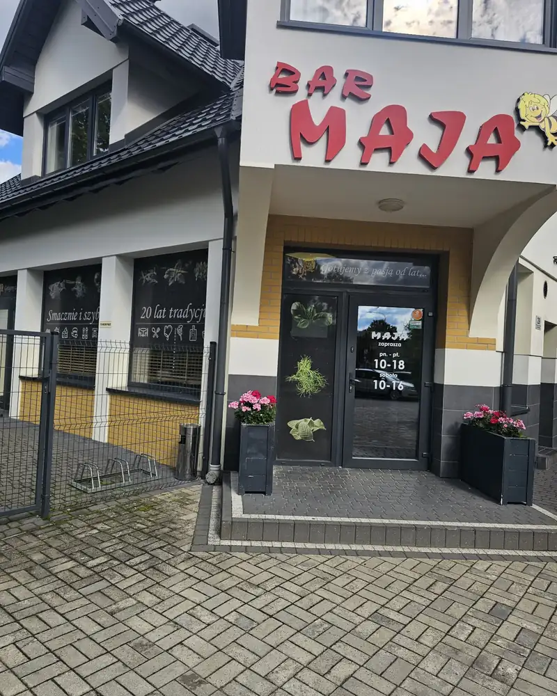 Budynek baru z czerwonym napisem BAR MAJA i pszczółką nad wejściem